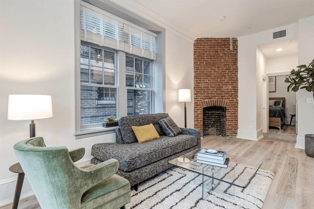 a living room with a couch and chairs and a brick fireplace